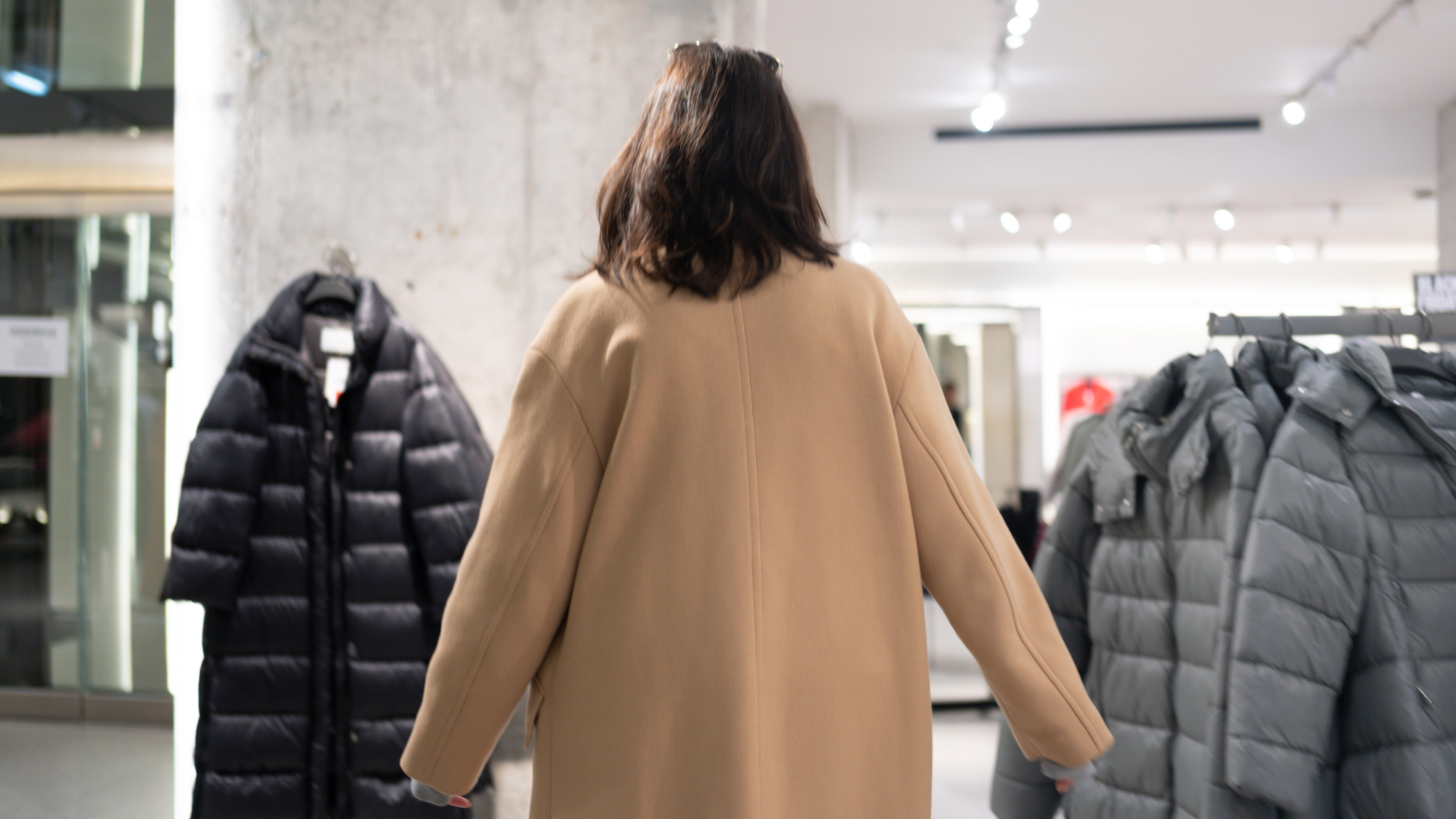 Rear view unrecognizable woman walking through clothing store